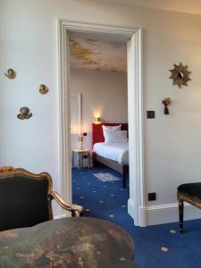 Habitación de hotel con cama y puerta que conduce a un dormitorio en Le Manoir Saint Thomas, en Amboise