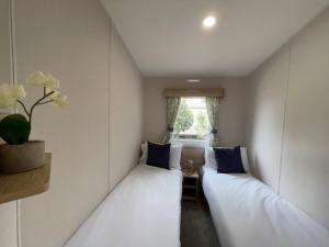 two beds in a small room with a window at Mersea Retreat in West Mersea