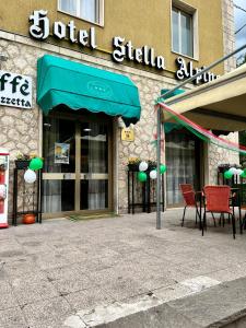 a store front with a green awning and tables and chairs at Hotel Stella Alpina in Villalago