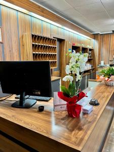 a desk with a computer and a vase of flowers on it at Hotel Stella Alpina in Villalago