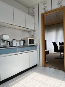 a kitchen with white cabinets and a room with chairs at Ferienwohnung Paulina in Braunschweig