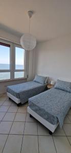 a bedroom with two beds and a large window at LAMAR SUITES Seafront Apartments in Misano Adriatico