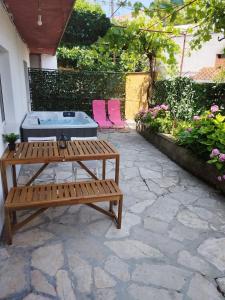 a patio with a table and two pink chairs at Apartmani Radić Rg in Rogoznica