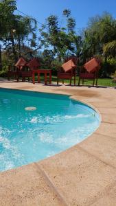 a swimming pool with two benches and chairs next to it at ALQUIMIA in Paso de la Patria