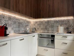 una cocina con armarios blancos y una pared de azulejos en Luxuria Modern Apartments - Self Check-in, en Šiauliai