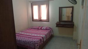 a small bedroom with a bed and a mirror at Chalet - Calipsio neighbourhood in Ras Sedr