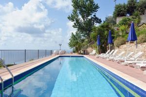 a swimming pool with chairs and blue umbrellas at Villa Del Conte in Drapia