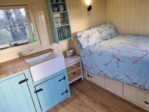a kitchen with a sink and a bed in a room at Delilah the shepherd's hut in Sidlesham