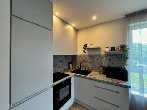 a kitchen with white cabinets and a sink and a window at Cozy family apartment near the old town in Klaipėda +11 photos