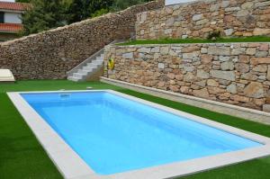 een groot blauw zwembad naast een stenen muur bij Casa en Tarela, Porto do Son in Porto do Son