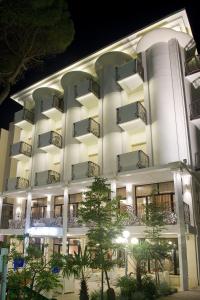 un grande edificio bianco con balconi di notte di Hotel Baby B&B a Milano Marittima