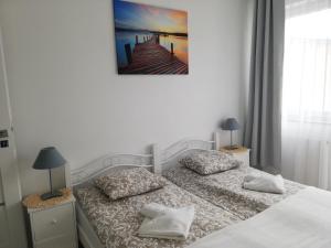 a bedroom with two beds and a picture on the wall at Apartament Kapitalny in Dziwnówek