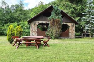 una mesa de picnic y bancos frente a un edificio en Máréfalvi vendégház, en Băile Homorod