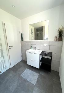 ein weißes Badezimmer mit einem Waschbecken und einem Spiegel in der Unterkunft Haus Oskar in Hahn