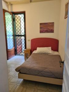 1 dormitorio con 1 cama con cabecero rojo en La casa di Nataly, en Fregene