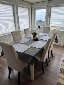 a dining room with a table with chairs and windows at Barents sea window in Ytre Kiberg