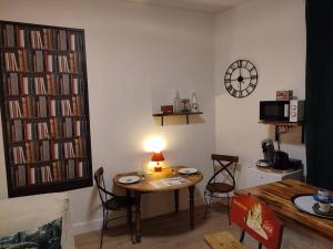 a living room with a table and chairs and a clock at Déco Vintage - 5mn du centre - TV connectée in Pau +18 photos