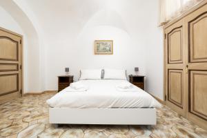 sypialnia z białym łóżkiem i drewnianymi drzwiami w obiekcie A casa di Antonio w mieście Positano