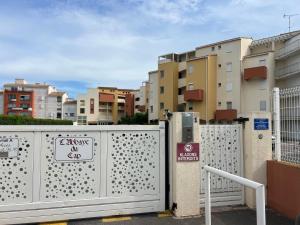 einen Zaun mit einem Schild neben den Gebäuden in der Unterkunft Belle vue in Cap d'Agde