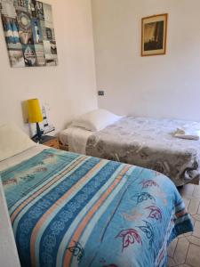 1 dormitorio con 2 camas y lámpara. en La casa di Nataly, en Fregene