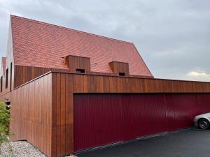 een rood gebouw met twee garagedeuren en een auto bij Appartements de Manon au cœur des vignes in Kientzheim