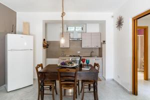 a kitchen with a wooden table with chairs and a refrigerator at LuMia in Aci Castello