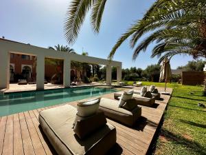 a swimming pool with chaise lounge chairs next to a house at Les Jardins de Kesali in Marrakesh