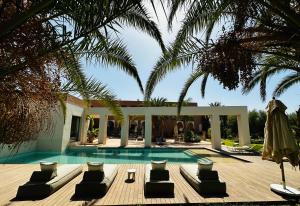 a pool with chaise lounge chairs and a house at Les Jardins de Kesali in Marrakesh