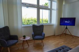 sala de estar con 2 sillas y TV de pantalla plana en Ruhiges Apartment am Wörthersee mit Tiefgarage, en Krumpendorf am Wörthersee