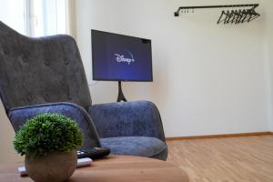 a living room with a chair and a tv at Ruhiges Apartment am Wörthersee mit Tiefgarage in Krumpendorf am Wörthersee