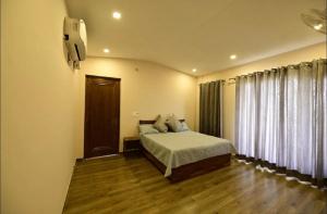 a bedroom with a bed and a tv on the wall at Farm Stay in Neemrana I 3 BHK with Pool & Chef I Close to Nature - Poshpad in Behror