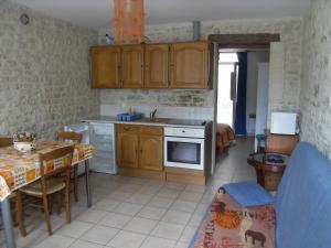 a kitchen with wooden cabinets and a table and a kitchen with a dining room at Maison en Pierre in Port-en-Bessin-Huppain