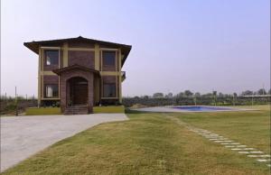 a small house with a grassy yard in front at Farm Stay in Neemrana I 3 BHK with Pool & Chef I Close to Nature - Poshpad in Behror