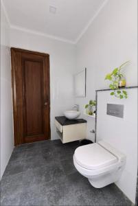 a white bathroom with a toilet and a sink at Farm Stay in Neemrana I 3 BHK with Pool & Chef I Close to Nature - Poshpad in Behror