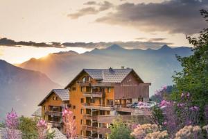 un edificio su una collina con montagne sullo sfondo di Chalet 4 pers. Piscine et literie toute neuve. a Puy-Saint-Vincent