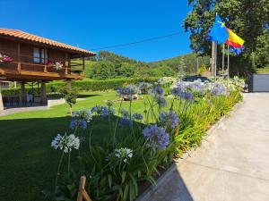 a garden with purple flowers and a house at APARTAMENTOS VALLE DE IROLA in Luanco