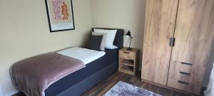 a small bedroom with a bed and a wooden cabinet at Pension Kalbach by Marion in Mittelkalbach