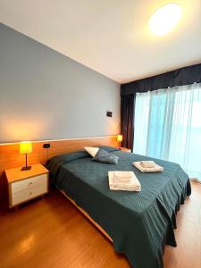 a bedroom with a large bed with a green blanket at Hotel Alemagna in Bibione