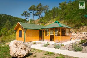 une petite maison avec un grand rocher en face dans l'établissement Air Zaovine, à Bajina Bašta