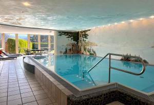 ein großes Schwimmbad in einem Gebäude mit einem großen Schwimmbad in der Unterkunft Hotel Am Hirschhorn - Wellness - Spa - and more in Wilgartswiesen