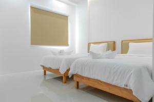 two beds with white sheets and a window in a room at S1 Trang Hotel in Trang