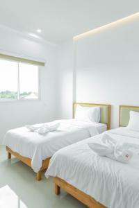 two beds in a white room with a window at S1 Trang Hotel in Trang