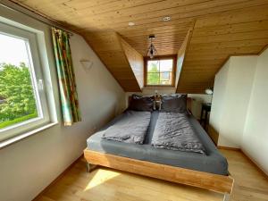 uma cama num pequeno quarto com tecto em madeira em Bergblick em Weilheim in Oberbayern