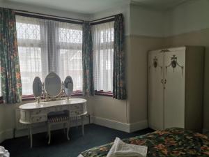 um quarto com um toucador com um espelho e uma cama em Single Bedroom available - Train station London Seven Kings em Seven Kings