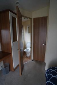 a bathroom with a toilet and a door open at Manor at Manor Park Hunstanton WiFi pets go free in Hunstanton