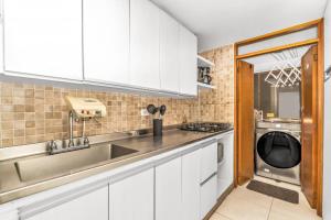 a kitchen with white cabinets and a sink and a dishwasher at A walk to the beach in Cartagena de Indias