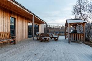 eine Holzterrasse mit einem Picknicktisch und einem Pavillon in der Unterkunft Húsafell holiday homes in Húsafell