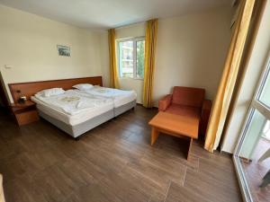 a bedroom with a bed and a chair and a window at Family Hotel Romantik in Sunny Beach