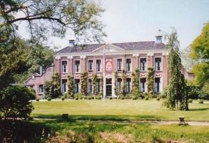 een groot roze huis op een groen veld bij Schaapskooi 20 in Dwingeloo