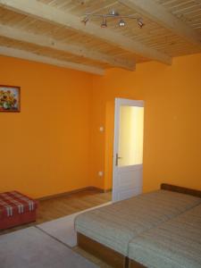 een slaapkamer met oranje muren en een deur bij Sárgarigó Vendégház in Bakonybél